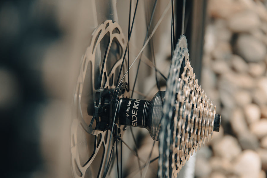A Sidekick rear hub between the brake rotor and cassette, close up from the drive side, with a rock wall soft behind it.